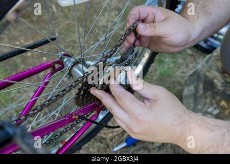 Mécanicien réparateur installant l'assemblage ou le réglage de l'engrenage de vélo sur la roue Banque D'Images