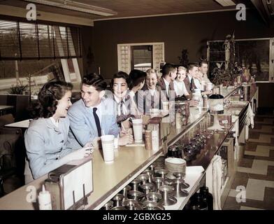 GROUPE D'ADOLESCENTS DES ANNÉES 1950, GARÇONS ET FILLES ASSIS AU COMPTOIR DE LA FONTAINE DE SODA, EN TRAIN DE DISCUTER ENSEMBLE - F6763C CRÈME D'INTÉRIEUR HAR001 HARS COMPTOIR MANGER DATE À L'INTÉRIEUR NOSTALGIQUE 4 FLIRTING DINER SUBURBAIN SODA ALLER FONTAINE VILLE COULEUR PAILLE JONQUE VIEUX TEMPS FLIRT NOSTALGIE FRÈRE VIEILLE MODE SOEUR HAMBURGER JUVÉNILE COMMUNICATION RIRE SERVIR AMI MILKSHAKE MEILLEUR SNACK SUCRÉ JOIE STYLE DE VIE GROGNUP COPIE ESPACE AMITIÉ ASSEYEZ-VOUS COPAIN ADOLESCENTE ADOLESCENT GARÇON AMERICANA CAFE PETITE AMIE KETCHUP TÊTE ET ÉPAULES BOISSON SERVICE À LA CLIENTÈLE SNACK REPAS COMPTOIR SUSPENDU HORS LINOLÉUM STABLE SODA FONTAINE RIRE MALT Banque D'Images