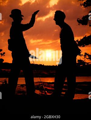 SILHOUETTE ANONYME DE DEUX HOMMES DANS LES ANNÉES 1950, UN PORTANT UN CHAPEAU TENANT UNE CANNE À PÊCHE, RACONTANT L'HISTOIRE DE LA GRANDE QUI S'EST MISE EN ROUTE - KA1570 HAR001 HARS ROD SILHOUETTES HUMOUR TAILLE AVENTURE LOISIR DÉMÊLANT LOISIRS COMIQUE RACONTER CONNEXION COMÉDIE CONCEPTUELLE COMÉDIE ANLING EXAGÉRATION ANONYME EST DEVENU UN CONTE DE GRANDE HISTOIRE HAR001 OLD FASHIONED Banque D'Images