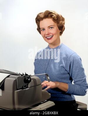 PORTRAIT SOURIANT DES ANNÉES 1950 SECRÉTAIRE ASSIS DERRIÈRE LA MACHINE À ÉCRIRE - O1276C HAR001 PERLES HARS JEUNE AMI DE COMMUNICATION ADULTE COMMIS ADJOINT FEMMES JOBS STUDIO PORTRAITS SANTÉ ASSIS ESPACE DE COPIE DEMI-LONGUEUR FEMMES PERSONNES OEIL CONTACT BONHEUR DACTYLOGRAPHIE SERVICE À LA CLIENTÈLE EMPLOIS DE TRAVAIL DE BUREAU SOURIRES GAL VENDREDI MACHINE À ÉCRIRE MANUELLE ADMINISTRATEUR SECRÉTAIRES STYLISTES STYLISTES STRAND AMANENSIS CARDIGAN JEUNES FEMMES ADULTES JEUNES CAUCASIENS ETHNICITÉ CLÉRICALE HAR001 ANCIEN DACTYLOGRAPHE Banque D'Images
