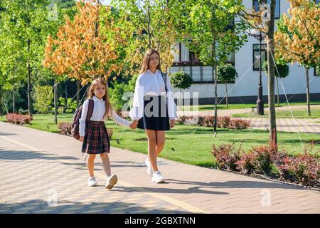 Deux sœurs filles tiennent la main et vont à l'école ensemble le matin Banque D'Images