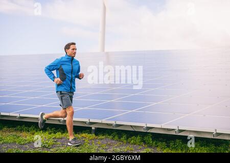 Active style de vie jeune homme coureur courir par panneaux solaires ferme à l'extérieur arrière-plan d'été Banque D'Images