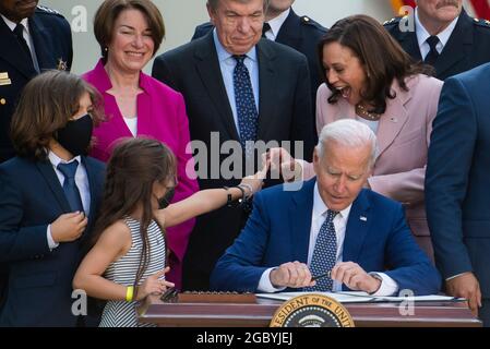 Avec son frère Logan Evans regardant à gauche, Abigail Evans, fille du policier du Capitole tué William “Billy” Evans, se rend au vice-président des États-Unis Kamala Harris tandis que le président des États-Unis Joe Biden signe H.R. 3325, « Loi décernée quatre médailles d’or au Congrès à la police du Capitole des États-Unis et à ceux qui ont protégé le Capitole des États-Unis le 6 janvier 2021 », entrée en vigueur dans le jardin des roses de la Maison Blanche à Washington, DC, le jeudi 5 août 2021. Crédit : Rod Lamkey/CNP/MediaPunch Banque D'Images