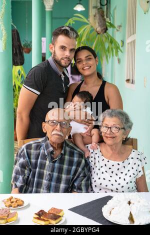 Couple âgé assis. Un homme et une femme avec un enfant dans les bras debout derrière les personnes âgées Banque D'Images