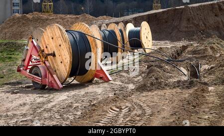 Câble électrique haute tension en rouleau ou bobine ronde au sol. Concept de fourniture d'électricité pour les projets de construction. Plusieurs bobines en bois avec puissance Banque D'Images