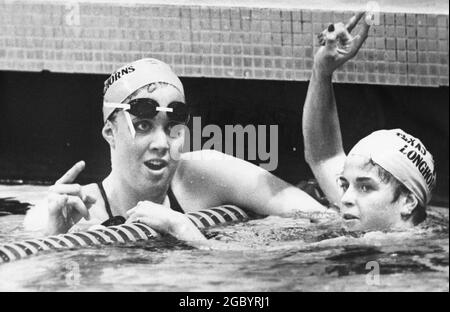 Austin, Texas USA, 1986: Le nageur de l'Université du Texas Tiffany Cohen, à gauche, et un coéquipier flash le signe 'hook 'em Hornss' à la fin d'une course pendant une réunion de natation à l'université. ©Bob Daemmrich Banque D'Images