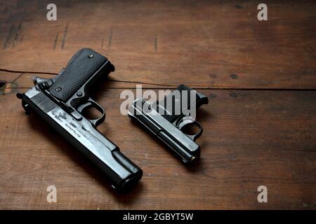 Canons sur fond en bois. Deux armes de pistolet en métal noir, armes de poing automatiques pour la protection et l'attaque sur une table vintage. Vue latérale Banque D'Images