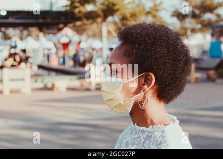 Femme africaine avec afro portant un masque de protection jaune au soleil Banque D'Images