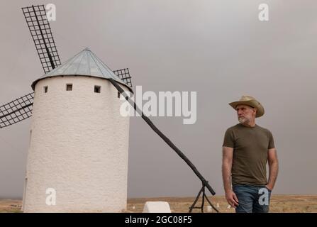 Un homme portant un chapeau de cow-boy avec des moulins à vent dans la campagne Banque D'Images