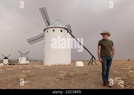 Un homme portant un chapeau de cow-boy avec des moulins à vent dans la campagne Banque D'Images