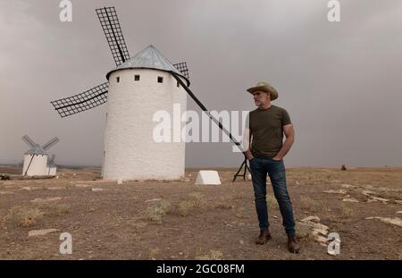 Un homme portant un chapeau de cow-boy avec des moulins à vent dans la campagne Banque D'Images