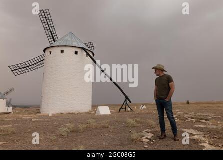 Un homme portant un chapeau de cow-boy avec des moulins à vent dans la campagne Banque D'Images