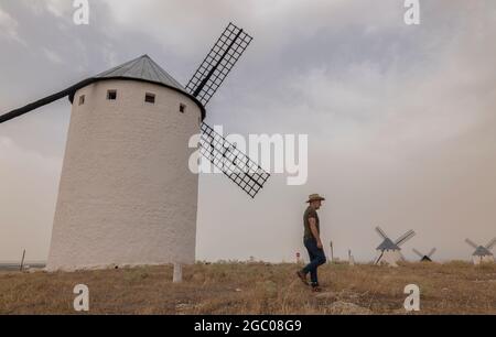 Un homme portant un chapeau de cow-boy avec des moulins à vent dans la campagne Banque D'Images