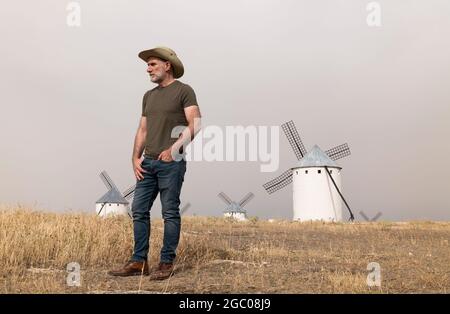 Un homme portant un chapeau de cow-boy avec des moulins à vent dans la campagne Banque D'Images