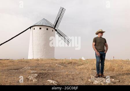 Un homme portant un chapeau de cow-boy avec des moulins à vent dans la campagne Banque D'Images