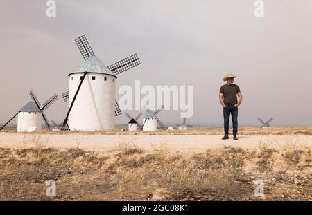 Un homme portant un chapeau de cow-boy avec des moulins à vent dans la campagne Banque D'Images