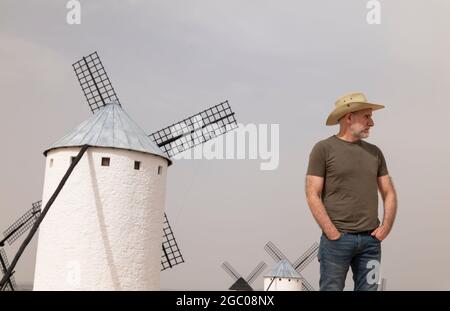 Un homme portant un chapeau de cow-boy avec des moulins à vent dans la campagne Banque D'Images