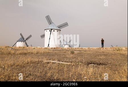 Un homme portant un chapeau de cow-boy avec des moulins à vent dans la campagne Banque D'Images