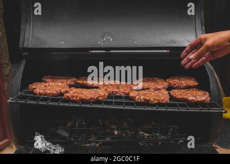 Hamburgers sur le gril avec le fromage gorm fondu sur la viande. Viande cuite sur le gril et charbon de bois. Chauffer sur la viande pour la cuisson. Viande grillée pour le bu Banque D'Images