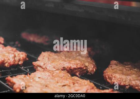 Hamburgers sur le gril avec le fromage gorm fondu sur la viande. Viande cuite sur le gril et charbon de bois. Chauffer sur la viande pour la cuisson. Viande grillée pour le bu Banque D'Images