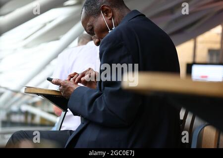 Un homme noir travaillant sur son smartphone à une gare de Londres Banque D'Images