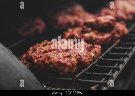 Hamburgers sur le gril avec le fromage gorm fondu sur la viande. Viande cuite sur le gril et charbon de bois. Chauffer sur la viande pour la cuisson. Viande grillée pour le bu Banque D'Images