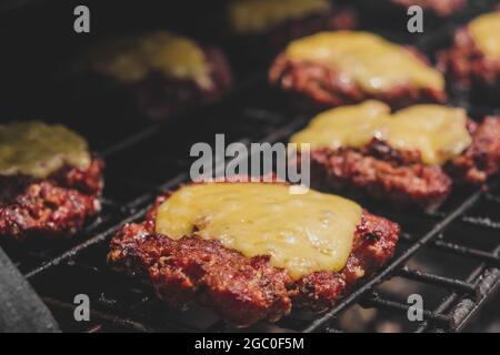 Hamburgers sur le gril avec le fromage gorm fondu sur la viande. Viande cuite sur le gril et charbon de bois. Chauffer sur la viande pour la cuisson. Viande grillée pour le bu Banque D'Images