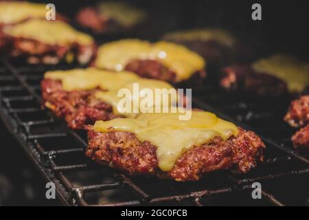 Hamburgers sur le gril avec le fromage gorm fondu sur la viande. Viande cuite sur le gril et charbon de bois. Chauffer sur la viande pour la cuisson. Viande grillée pour le bu Banque D'Images