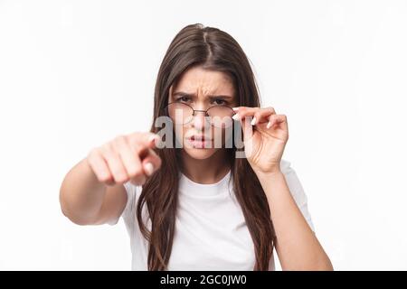 Gros plan portrait d'une femme suspecte, judgmentale dans des lunettes, blâmer quelqu'un, frognant, se calant sur la personne qu'elle blâme, pointant des accusations de doigt Banque D'Images