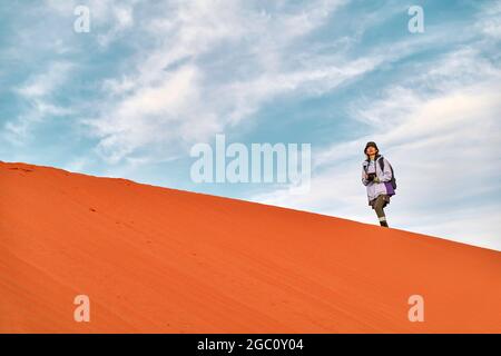 femme asiatique photographe marchant sur la crête d'une dune de sable regardant la vue Banque D'Images