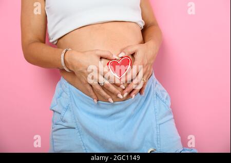 La femme enceinte qui attend un enfant caresse son ventre Banque D'Images