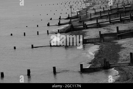 Image en noir et blanc des groynes vues sur la plage de Bognor Regis ralentissant toute érosion de plage. Banque D'Images