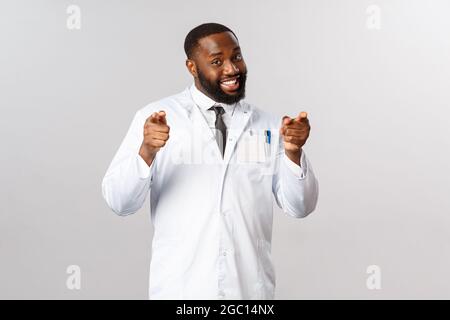 Portrait d'un sympathique médecin pointant vers l'appareil photo, invitant les gens à vérifier, en disant rester à la maison être sûr pendant la corona, covid19 pandémie Banque D'Images