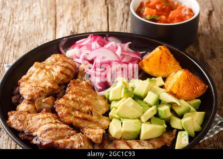 POC chuc est un plat de viande mexicain composé de fines côtelettes de porc marinées dans du jus d'orange dans l'assiette sur la table. Horizontale Banque D'Images