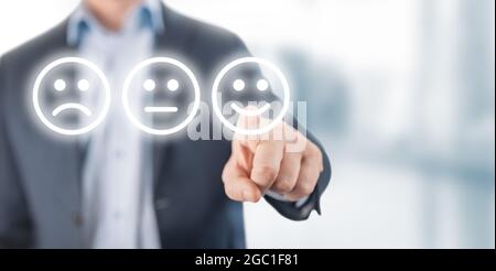 Concept de notation. Homme choisissant sourire heureux visage émotion sur fond flou. Main d'homme d'affaires pointant l'icône de visage smiley de l'écran comme frais positifs Banque D'Images