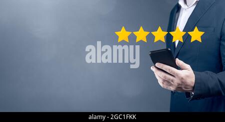 Note 5 étoiles 5 avec écran tactile pour homme d'affaires, concept sur les commentaires et les avis positifs des clients, excellentes performances. Homme d'affaires pointant Banque D'Images