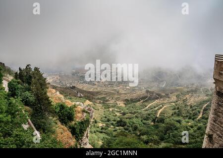 Vue de Erice, Sicile, Italie. Ville historique au sommet des montagnes surplombant le paysage et la mer. Vue sur la belle campagne luxuriante dans les nuages. Banque D'Images