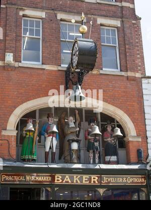 Cinq personnages, dont Old Father Time et un soldat britannique, tous vêtu d'une tenue traditionnelle au-dessus d'un magasin à Gloucester, au Royaume-Uni Banque D'Images