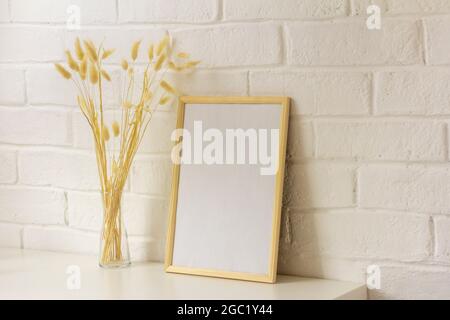 Un cadre photo vide et des fleurs séchées dans un vase sur la table avec une copie de l'espace.style scandinave Banque D'Images