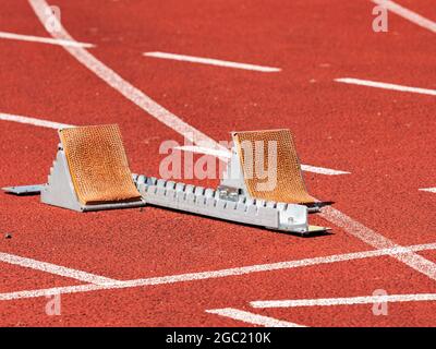 Blocs de starting vides à la cour du stade d'athlétisme. Chenilles de glissière peintes sur du tampon rouge Banque D'Images