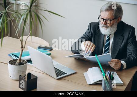 Portrait d'un homme âgé à tête grise, professeur, enseignant vérifiant les devoirs des élèves en classe, à l'intérieur. Concept de profession professionnelle, emploi Banque D'Images