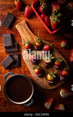 Photo de fraises enrobées de chocolat maison sur une planche de bois Banque D'Images