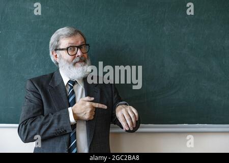 Portrait de l'homme à tête grise aîné, professeur, enseignant travaillant au travail, à l'intérieur. Concept de profession, d'emploi, d'éducation et de motivation professionnels. Banque D'Images