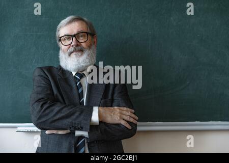 Portrait de l'homme à tête grise aîné, professeur, enseignant travaillant au travail, à l'intérieur. Concept de profession, d'emploi, d'éducation et de motivation professionnels. Banque D'Images