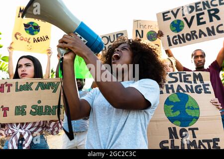 Groupe de militants protestant contre le changement climatique - des gens multiraciaux qui luttent sur la route brandissent des banderoles sur les catastrophes naturelles Banque D'Images