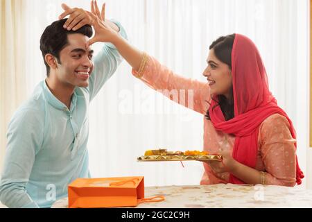 UNE SŒUR HEUREUSE CÉLÉBRANT LES RITUELS TRADITIONNELS SUR RAKSHABANDHAN AVEC SON FRÈRE Banque D'Images