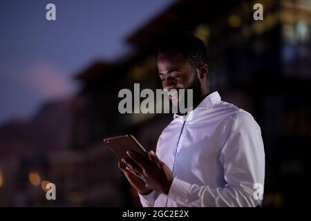 Homme d'affaires afro-américain travaillant la nuit avec un smartphone Banque D'Images