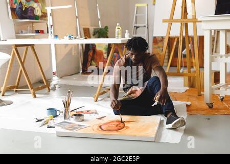Artiste peintre afro-américain au travail peint portrait sur toile dans un studio d'art Banque D'Images