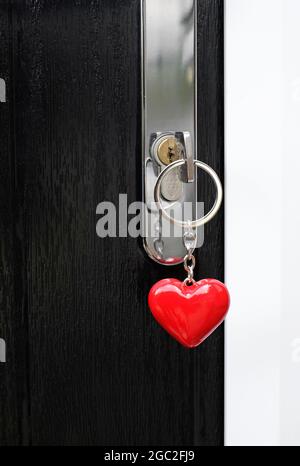 clé de maison sur porte-clés en forme de coeur rouge dans la serrure de porte Banque D'Images