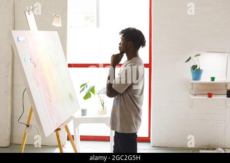 Artiste peintre afro-américain à l'œuvre regardant des œuvres d'art dans un studio d'art Banque D'Images